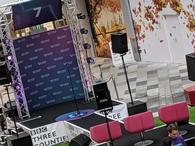 Stage set with truss, speakers, seating and branded backdrop